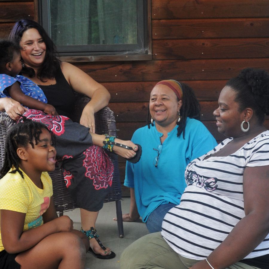 Rachel Zaslow sitting with a child on her lap, surrounded by women.