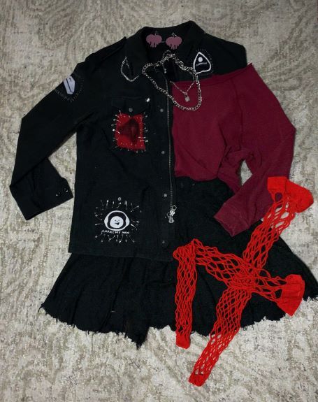 outfit with black jacket with red patch, red longsleeve, a black skirt, and red fishnet stockings